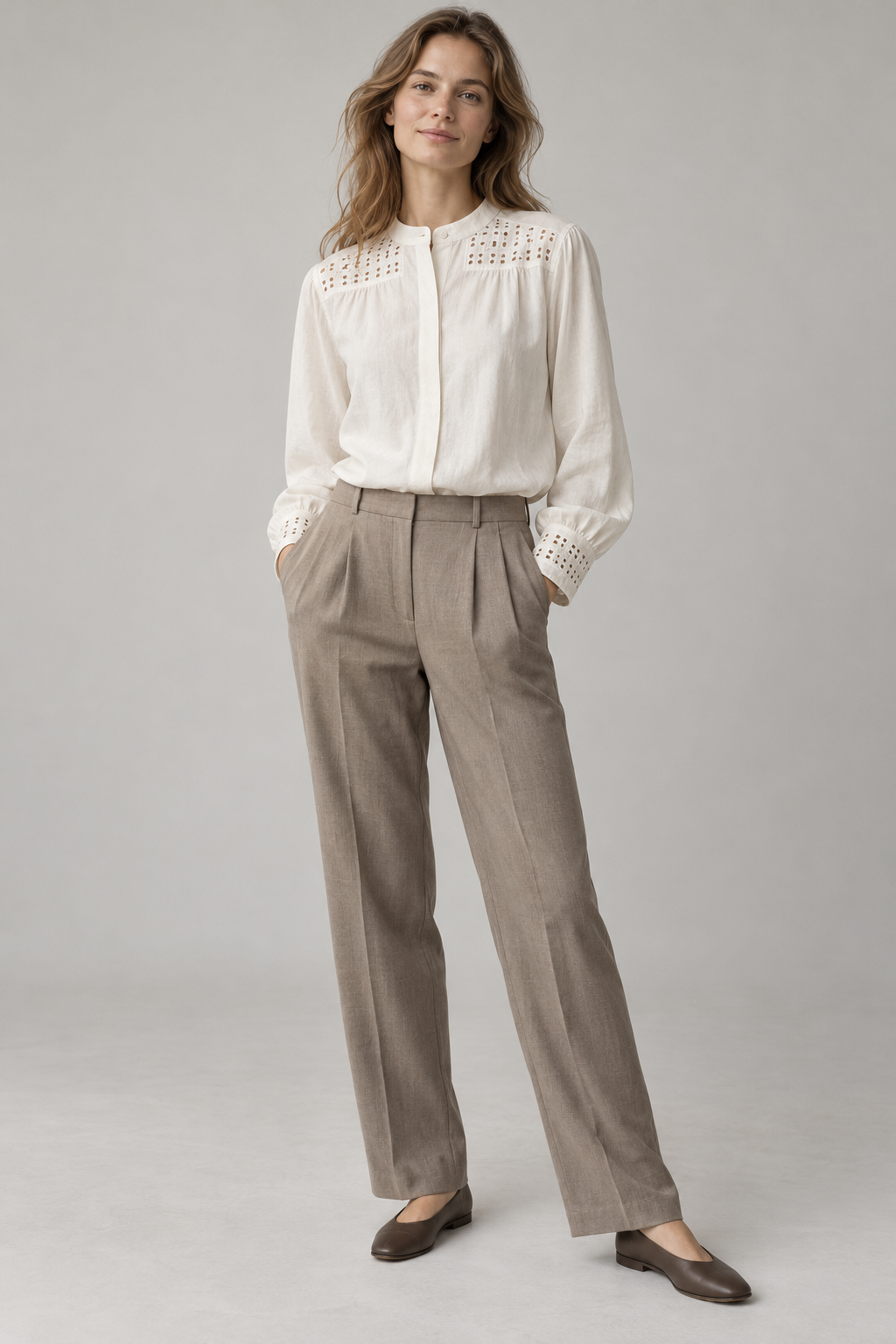 AI-generated design concept of an ivory blouse with localised cutwork at the shoulder yokes and cuffs, styled with taupe trousers, not a completed sample